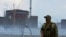 FILE - A serviceman with a Russian flag on his uniform stands guard near the Zaporizhzhia nuclear power plant in the course of Ukraine-Russia conflict outside the Russian-controlled city of Enerhodar in the Zaporizhzhia region, Ukraine, Aug. 4, 2022. 