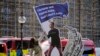A protester adjusts an installation depicting Mark Zuckerberg surfing on a wave of cash constructed outside parliament in London, Oct. 25, 2021, where Facebook whistleblower Frances Haugen was due to testify.