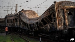 A railway worker stands next to heavily damaged train after a Russian attack on a train station yesterday during Ukraine's Independence Day in the village Chaplyne, Ukraine, Aug. 25, 2022.