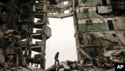 FILE - A resident looks for belongings in an apartment building destroyed during fighting between Ukrainian and Russian forces in Borodyanka, Ukraine, April 5, 2022. Russia's invasion of Ukraine started six months ago.