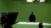FILE - Masheed Barzz, an Afghan presenter for 1TV channel, appears on camera with her face covered by a veil in Kabul on May 25, 2022. Female journalists are banned from state-run media outlets, and those in the private sector can appear on TV only if their faces are covered. 