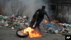 A protester kicks a burning tire during a protest in Port-au-Prince, Haiti, Aug. 22, 2022.