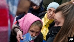 People fleeing Ukraine hand in their passports as they register for a bus which will take them to Germany, at the train station in Przemysl, Poland, March 3, 2022.