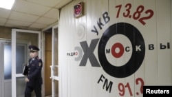 FILE - An Interior Ministry officer walks inside the office of Russian radio station Ekho Moskvy, in Moscow, Russia, Oct. 23, 2017.