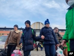 Disabled children are escorted to waiting buses, in Zahony, Hungary, March 2, 2022, after being evacuated from two orphanages in Kyiv, Ukraine.