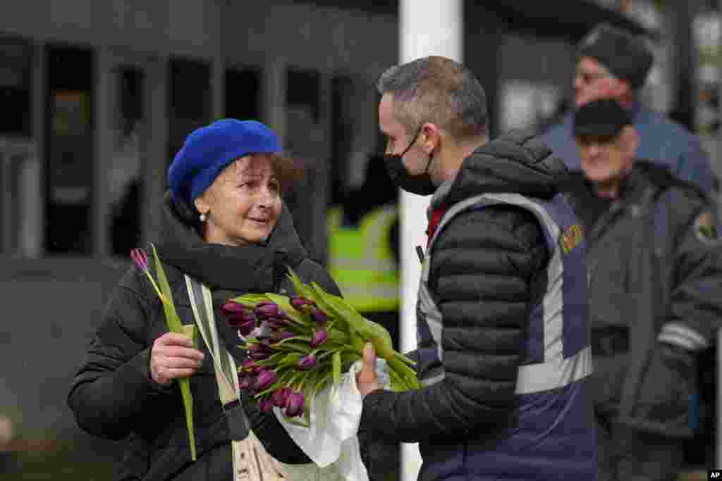 A Romanian Immigrations officer gives flowers to a refugee fleeing the conflict from neighboring Ukraine after she crossed the border on International Women's Day, at the Romanian-Ukrainian border, in Siret, Romania, March 8, 2022.