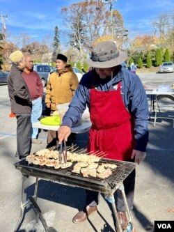 Relawan di IMAAM Center mempersiapkan makanan khas Indonesia, seperti sate ayam, bagi para pemilih yang sudah berikan suara. Para pemilih gembira dengan tersedianya makanan dan minuman hangat ini karena pemilu berlangsung di tengah udara dingin.