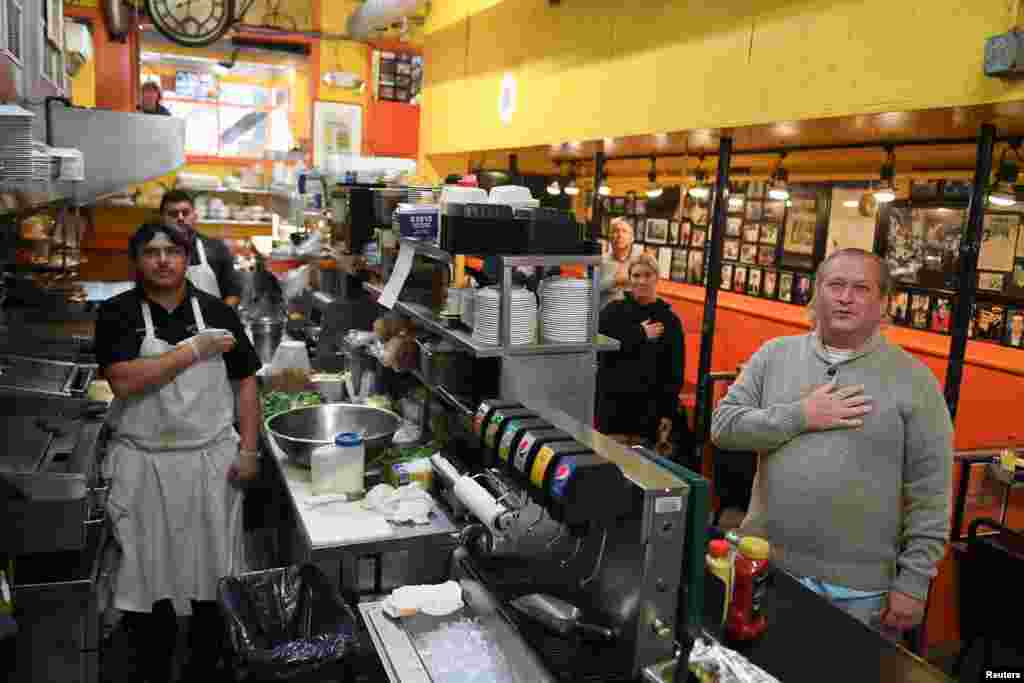 Franklin Garcia, line cook and Robert F. Bussink III, customer, recite the Pledge of Allegiance at Chick and Ruth’s Delly on election day in Annapolis, Maryland, Nov. 8, 2022. 