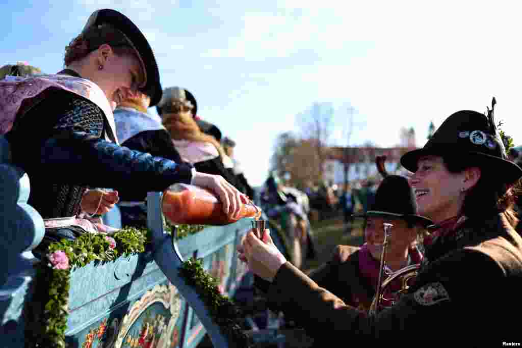 Farmers' wives, dressed in traditional Bavarian costumes, give out schnapps from a wooden carriage, to the people on the way to the chapel on the Kalvarienberg during the Leonhardi Ritt procession, to pray to St. Leonhard, the patron saint of animals, in Bad Toelz, Germany.