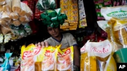 A vendor shows packs of cooking oil at his stall at a market in Jakarta, Indonesia, Sunday, April 17, 2022.