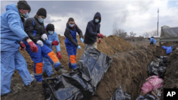 Warga Ukraina memasukkan jenazah korban perang ke kuburan massal di pinggiran kota Mariupol, Ukraina, 9 Maret 2022, karena orang tidak dapat menguburkan mereka di tengah tembakan artileri pasukan Rusia (ilustrasi). 