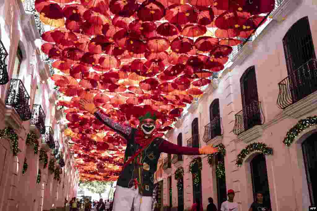 Un hombre sobre zancos vestido como un personaje navideño actúa para los turistas que visitan el centro histórico de Caracas el 30 de diciembre de 2022, en la víspera de las celebraciones de fin de año. [AFP]