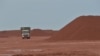 Sebuah truk membawa material di samping tumpukan material bauksit di tambang milik grup Harita di Kendawangan, Kalimantan Barat, 13 Februari 2017. (ADEK BERRY / AFP)