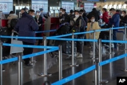 北京國際機場一個國際航班櫃枱的旅客等候託運行李。（2022年12月29日）