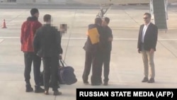 This video grab taken from a footage shown by Russian state media that AFP couldn't independantly authentify shows US basketball star Brittney Griner (L) during a swap of prisoner with Viktor Bout (2ndR), a Russian notorious arms dealer on December 8, 2022 on the tarmac of Abu Dhabi airport. - Griner, 32, who was arrested in Russia in February on drug charges, and Viktor Bout, 55, who was serving a 25-year sentence in a US prison, were exchanged at an airport in Abu Dhabi. In footage released by Russian state media, Griner, shorn of her distinctive dreadlocks, and a relaxed and animated Bout could be seen crossing paths on the airport tarmac and heading towards the planes that would take them home. (Photo by Russian State Media / AFP)