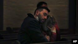 FILE - Michael Lo Piano, left, comforts Oksana Hryvinska, as they listen to Ukrainian folk songs during a benefit concert for Ukraine at St. Thomas More Catholic Chapel in New Haven, Conn., March 16, 2022.