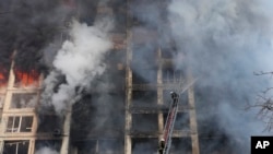Firefighters work in an apartment building damaged by shelling in Kyiv, Ukraine, Tuesday, March 15, 2022. (AP Photo/Efrem Lukatsky)