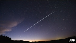 FILE - In this file photo taken Feb. 7, 2021, a long-exposure image shows a trail of a group of SpaceX's Starlink satellites passing over Uruguay as seen from the countryside some 185 kilometers north of Montevideo.