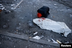 A man mourns next to the body of his mother, who was killed when an intercepted missile hit a residential building, during Russia's invasion of Ukraine, in Kyiv, March 17, 2022.