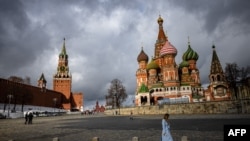 FILE - A woman walks near the Kremlin and St. Basil's Cathedral in central Moscow, Russia, Feb. 22, 2022. 