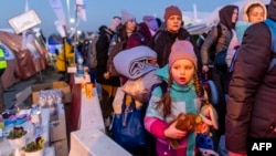 A little girl is seen as people line up to board buses at the Medyka Polish-Ukrainian border crossing on March 18, 2022.