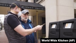 In this March 31, 2020 photo made available by World Central Kitchen, Chef Jose Andres, right, and Nate Mook discuss meal distribution to first responders in Washington, DC. 