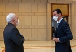 FILE - A picture released by the official Syrian Arab News Agency on April 20, 2020, shows President Bashar Al-Assad, right, meeting Iranian Foreign Minister Mohammad Javad Zarif in the Syrian capital Damascus.