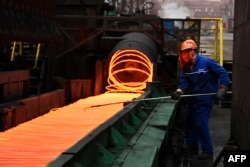 A Chinese employee sorts hot red steel at a steel plant in Zouping in China's eastern Shandong province on March 5, 2018.