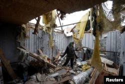 A woman removes debris inside a house destroyed during a Russian military attack in the village of Novooleksandrivka, in Kherson region, Ukraine Nov. 9, 2022.