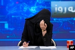 FILE - TV anchor Khatereh Ahmadi bows her head while wearing a face covering as she reads the news on TOLO NEWS, in Kabul, Afghanistan, May 22, 2022. Afghanistan's Taliban rulers require all female TV news anchors in the country to cover their faces while on-air.
