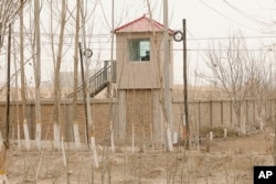FILE - A security person watches from a guard tower around a detention facility in Yarkent County in northwestern China's Xinjiang Uyghur Autonomous Region on March 21, 2021.