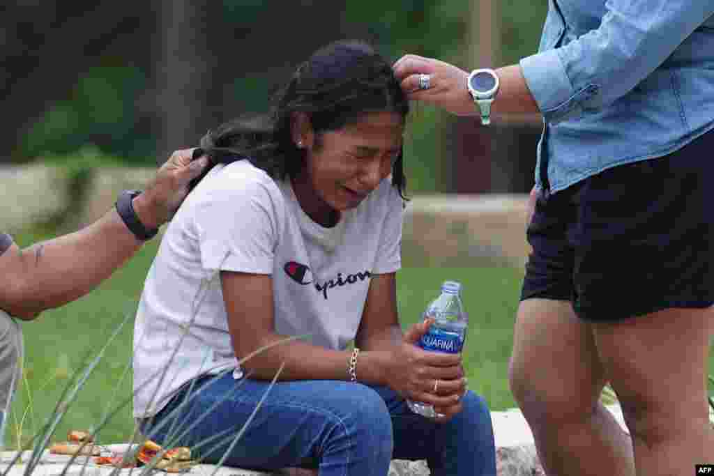 A girl cries, comforted by two adults, outside the Willie de Leon Civic Center where grief counseling will be offered in Uvalde, Texas, May 24, 2022.