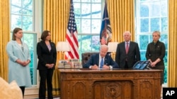 Rais Joe Biden akisaini kwenye White House sheria inayompa mamlaka mapya ya kusafirisha kwa haraka vifaa vya kijeshi kwenda Ukraine, May 9, 2022. Picha ya AP