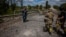 Soldiers of the Kraken Ukrainian special forces unit check a man's documents at a destroyed bridge on the road near the village of Rus'ka Lozova, north of Kharkiv, on May 16, 2022.