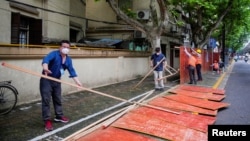 上海工人在拆除封閉街道的圍欄。 （2022年5月30日）