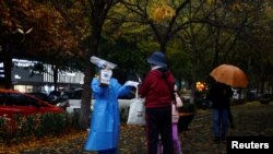 Seorang petugas mengenakan pakaian pelindung (APD) memandu orang untuk melakukan tes COVID-19 di Beijing, China 11 November 2022.