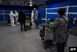 抵達上海浦東國際機場的乘客等候將要運載他們去隔離酒店的車輛。（2022年1月18日）