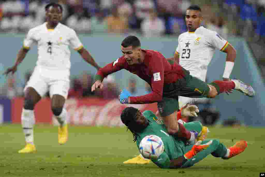 Portugal's Cristiano Ronaldo falls over Ghana's goalkeeper Lawrence Ati-Zigi during the World Cup group H soccer match between Portugal and Ghana, at the Stadium 974 in Doha, Qatar.