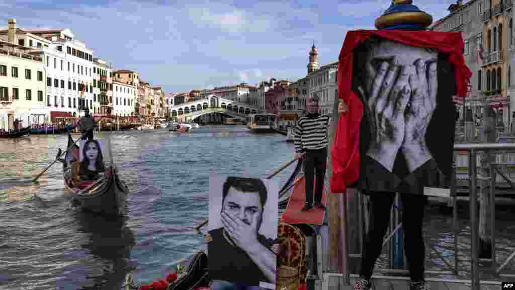 Gondoliers show pictures of models representing the three stages of silence: "I don't see, I don't hear, I don't speak", during a flash mob to mark the International Day of Violence against Women, on Venice's Grand Canal, near the Rialto Bridge.