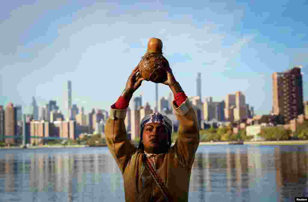 Chenae Bullock of The Shinnecock Indian Nation holds a traditional container of water during an indigenous sunrise water ceremony on the shore of the East River on Randall's Island in New York City as Indigenous Peoples' Day is observed in the U.S.