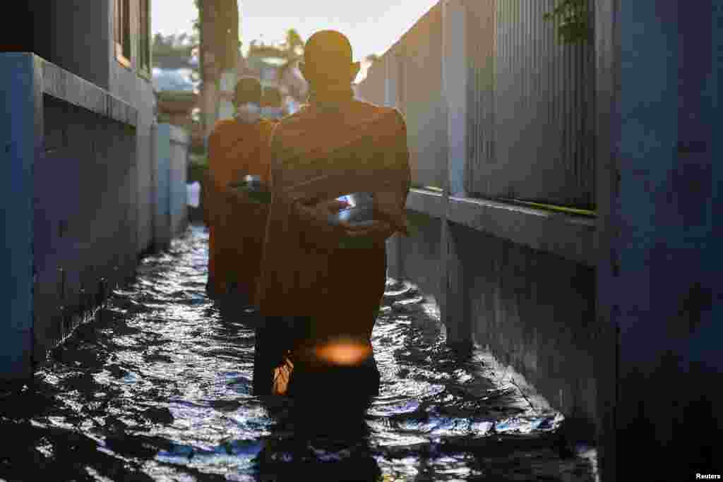 Monks walk to receive alms on a flooded street in Koh Kret in Nonthaburi, in the outskirts of Bangkok, Thailand.