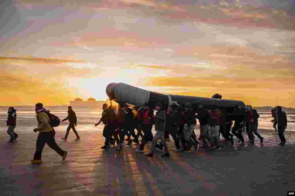 Migrants carry a smuggling boat as they prepare to embark on the beach of Gravelines, near Dunkirk, northern France, in a attempt to cross the English Channel.
