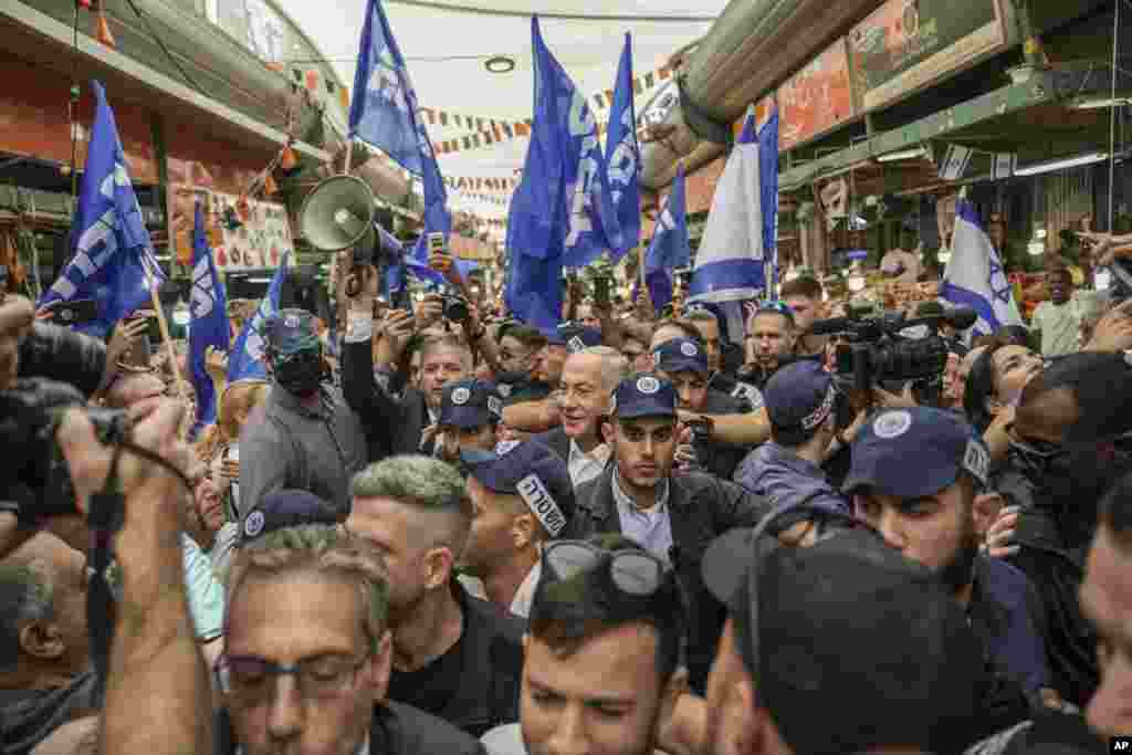 Former Israeli Prime Minister and the head of Likud party Benjamin Netanyahu, center, surrounded by security and his supporters visits at Hatikva Market in Tel Aviv during his campaign ahead of the country's Nov. 1 election.