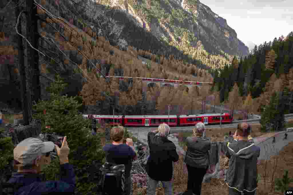 Members of the public take photos of a 1910-metre-long train with 100 cars passing near Bergun, Oct. 29, 2022, during a record attempt by the Rhaetian Railway (RhB) of the World's longest passenger train, to mark the Swiss railway operator's 175th anniversary.