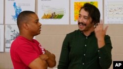 Environmental activist Reggie Carrillo, right, speaks with a community member, Friday, Sept 28, 2022, in Phoenix. Carrillo has benefited from one of several nonprofit initiatives to educate and engage residents about climate-fueled heat. (AP Photo/Matt York)