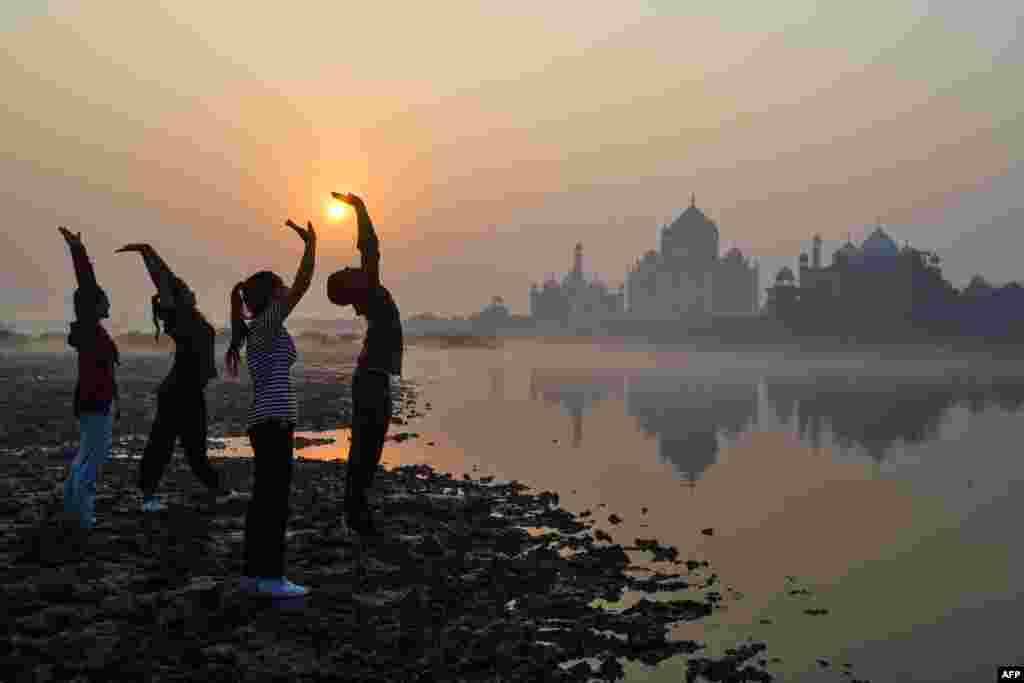Children exercise on the banks of the Yamuna River near the Taj Mahal in Agra at sunrise, India.