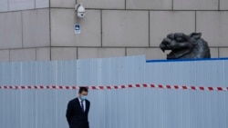 上海一家商场围栏外走过一名戴着口罩的工作人员。（2022年4月20日）