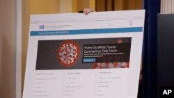 A poster displaying information from the White House Coronavirus Task Force is carried into the briefing room of the White House in Washington, Tuesday, March, 10, 2020, before Vice President Mike Pence and others arrive to speak. (AP Photo/Carolyn…
