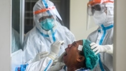 Medical staff take a swab sample from a woman to test for the COVID-19 novel coronavirus at a clinic in Insein, Yangon on September 21, 2020. (Photo by Ye Aung THU / AFP)