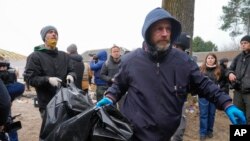 Policija nosi mrtvo tijelo jednog od šest civila - tri žene, jedne tinejdžerke i dva muškarca koji su pronađeni u Buči, blizu Kijeva, u Ukrajini, u utorak, 5. aprila 2022. godine.